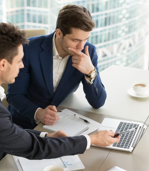 Entrepreneurs discussing work results on meeting Business partners using laptop while working together on important corporate project in office. Businessman attentively listening to adviser Investment specialist making presentation of promising deal